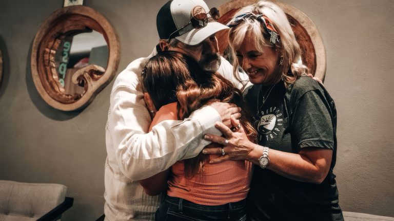 Troy and Leanna Brewer and others gathered in a close huddle, arms around one another.